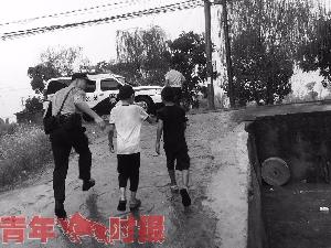 民警把两个孩子带上警车送他们回家。